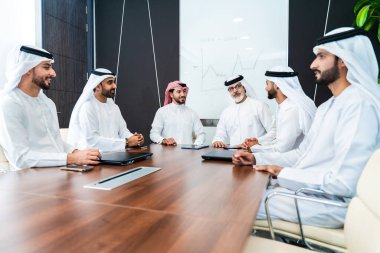 Bir grup Arap işadamı ofiste buluşuyor - Ortadoğulu iş adamları emirati kandora giyiyorlar, Dubai 'de bir toplantı odasında çalışıyorlar.