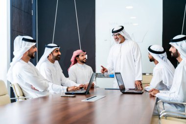 Bir grup Arap işadamı ofiste buluşuyor - Ortadoğulu iş adamları emirati kandora giyiyorlar, Dubai 'de bir toplantı odasında çalışıyorlar.