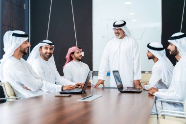 Bir grup Arap işadamı ofiste buluşuyor - Ortadoğulu iş adamları emirati kandora giyiyorlar, Dubai 'de bir toplantı odasında çalışıyorlar.