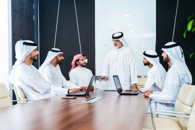 Bir grup Arap işadamı ofiste buluşuyor - Ortadoğulu iş adamları emirati kandora giyiyorlar, Dubai 'de bir toplantı odasında çalışıyorlar.