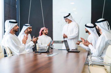 Bir grup Arap işadamı ofiste buluşuyor - Ortadoğulu iş adamları emirati kandora giyiyorlar, Dubai 'de bir toplantı odasında çalışıyorlar.