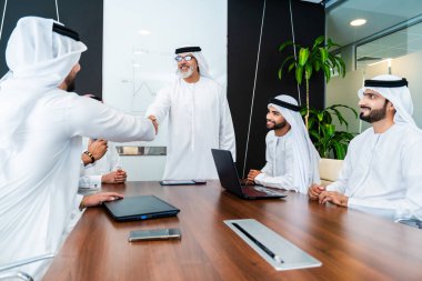 Bir grup Arap işadamı ofiste buluşuyor - Ortadoğulu iş adamları emirati kandora giyiyorlar, Dubai 'de bir toplantı odasında çalışıyorlar.