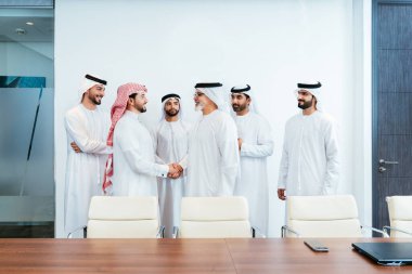 Bir grup Arap işadamı ofiste buluşuyor - Ortadoğulu iş adamları emirati kandora giyiyorlar, Dubai 'de bir toplantı odasında çalışıyorlar.