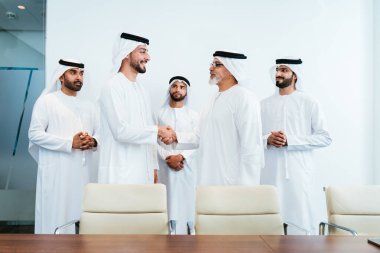 Bir grup Arap işadamı ofiste buluşuyor - Ortadoğulu iş adamları emirati kandora giyiyorlar, Dubai 'de bir toplantı odasında çalışıyorlar.