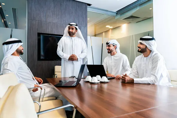 Bir grup Arap işadamı ofiste buluşuyor - Ortadoğulu iş adamları emirati kandora giyiyorlar, Dubai 'de bir toplantı odasında çalışıyorlar.