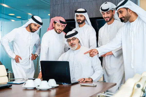 Bir grup Arap işadamı ofiste buluşuyor - Ortadoğulu iş adamları emirati kandora giyiyorlar, Dubai 'de bir toplantı odasında çalışıyorlar.
