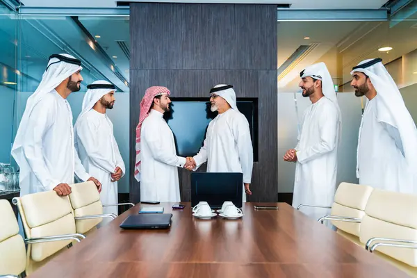 Bir grup Arap işadamı ofiste buluşuyor - Ortadoğulu iş adamları emirati kandora giyiyorlar, Dubai 'de bir toplantı odasında çalışıyorlar.