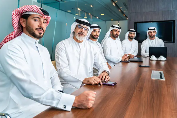 Bir grup Arap işadamı ofiste buluşuyor - Ortadoğulu iş adamları emirati kandora giyiyorlar, Dubai 'de bir toplantı odasında çalışıyorlar.