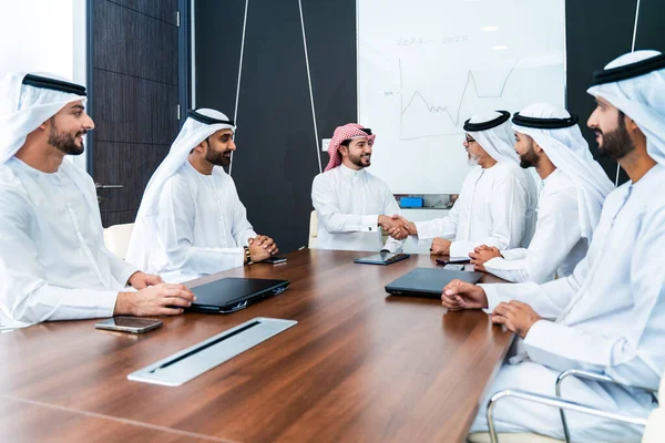 Bir grup Arap işadamı ofiste buluşuyor - Ortadoğulu iş adamları emirati kandora giyiyorlar, Dubai 'de bir toplantı odasında çalışıyorlar.