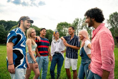 Çok ırklı bir grup genç parkta piknik yapmak için dışarıda zaman geçiriyorlar. Z kuşağı, yaşam tarzı ve arkadaşlık kavramları