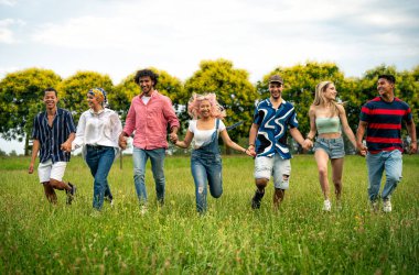 Çok ırklı bir grup genç parkta piknik yapmak için dışarıda zaman geçiriyorlar. Z kuşağı, yaşam tarzı ve arkadaşlık kavramları