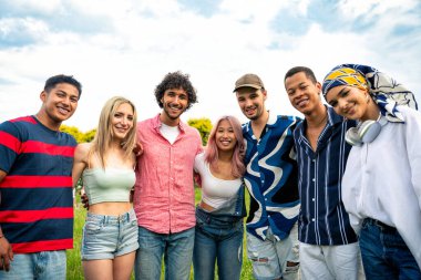 Çok ırklı bir grup genç parkta piknik yapmak için dışarıda zaman geçiriyorlar. Z kuşağı, yaşam tarzı ve arkadaşlık kavramları