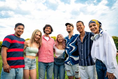 Çok ırklı bir grup genç parkta piknik yapmak için dışarıda zaman geçiriyorlar. Z kuşağı, yaşam tarzı ve arkadaşlık kavramları