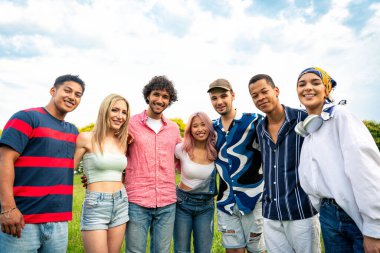 Çok ırklı bir grup genç parkta piknik yapmak için dışarıda zaman geçiriyorlar. Z kuşağı, yaşam tarzı ve arkadaşlık kavramları