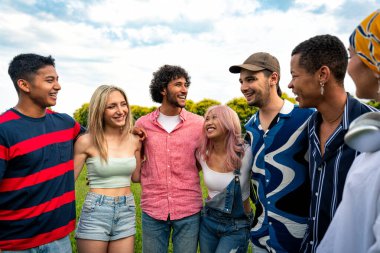 Çok ırklı bir grup genç parkta piknik yapmak için dışarıda zaman geçiriyorlar. Z kuşağı, yaşam tarzı ve arkadaşlık kavramları