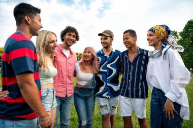 Çok ırklı bir grup genç parkta piknik yapmak için dışarıda zaman geçiriyorlar. Z kuşağı, yaşam tarzı ve arkadaşlık kavramları