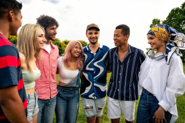 Çok ırklı bir grup genç parkta piknik yapmak için dışarıda zaman geçiriyorlar. Z kuşağı, yaşam tarzı ve arkadaşlık kavramları