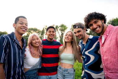 Çok ırklı bir grup genç parkta piknik yapmak için dışarıda zaman geçiriyorlar. Z kuşağı, yaşam tarzı ve arkadaşlık kavramları