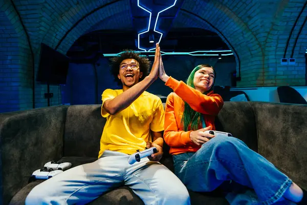 多种族的年轻朋友坐在沙发上玩电子游戏 电子游戏爱好者在电脑游戏主机上玩电子游戏很开心 — 图库照片