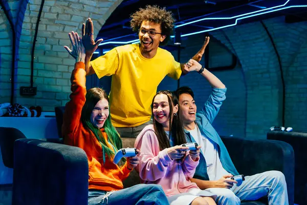 ソファーに座って自宅でビデオゲームをプレイする若い友人の複数のグループ コンピュータのビデオゲームコンソールでEスポーツをする楽しいビデオゲーム — ストック写真