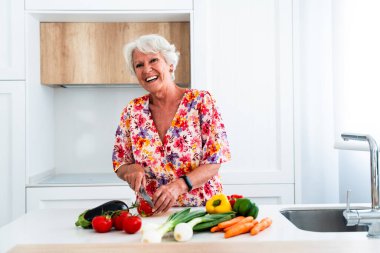 Gri saçlı, evde yemek pişiren yaşlı, güzel bir kadın. Genç, yaşlı bir büyükanne evde kaliteli vakit geçiriyor.