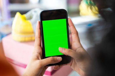 Güzel İspanyol bir kadın ev kıyafetleri ticareti işini evden yönetiyor - çevrimiçi alışveriş mağazası, cep telefonu yeşil ekranına yakın çekim - ev işi kavramı