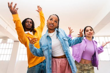 Çok ırklı hip-hop dansçılarından oluşan genç bir grup renkli sokak kıyafetleri giyip dans ediyorlar.