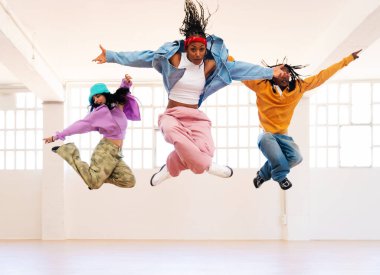 Çok ırklı hip-hop dansçılarından oluşan genç bir grup renkli sokak kıyafetleri giyip dans ediyorlar.