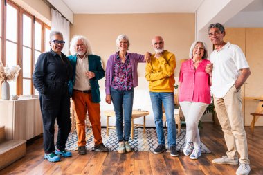 Bir grup mutlu kıdemli arkadaş, akşam yemeği için evde toplanıyor neşeli ve genç, yaşlı, çok ırklı insanlar eğleniyor.