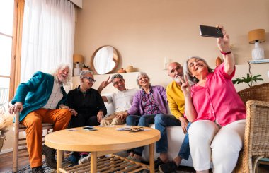 Bir grup mutlu kıdemli arkadaş, akşam yemeği için evde toplanıyor neşeli ve genç, yaşlı, çok ırklı insanlar eğleniyor.