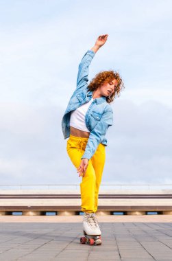 Güzel, kızıl saçlı, patenli, dışarıda eğlenen genç bir kadın şehirde paten sürerken kendine has bir tarzı olan güzel bir genç kız.