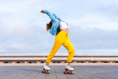 Güzel, kızıl saçlı, patenli, dışarıda eğlenen genç bir kadın şehirde paten sürerken kendine has bir tarzı olan güzel bir genç kız.