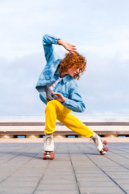 Güzel, kızıl saçlı, patenli, dışarıda eğlenen genç bir kadın şehirde paten sürerken kendine has bir tarzı olan güzel bir genç kız.
