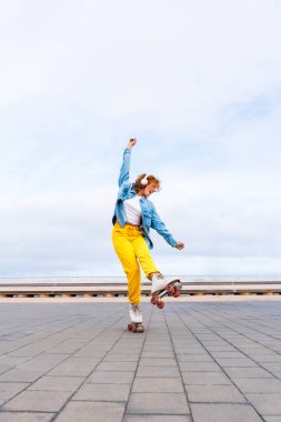 Güzel, kızıl saçlı, patenli, dışarıda eğlenen genç bir kadın şehirde paten sürerken kendine has bir tarzı olan güzel bir genç kız.