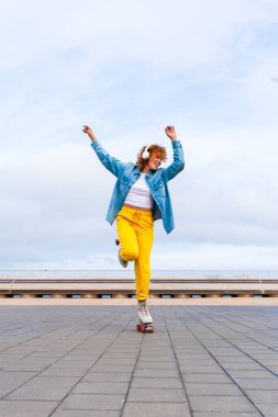 Güzel, kızıl saçlı, patenli, dışarıda eğlenen genç bir kadın şehirde paten sürerken kendine has bir tarzı olan güzel bir genç kız.