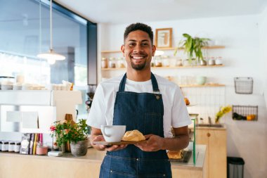 Fırın, kafede hamur işi, kahve ve fırında yemek servisi için hazır İspanyol siyahi bir adamın mutlu portresi. Restoran, kafe ve kendine güvenen garson barista servis, yardım ve hoş geldiniz.