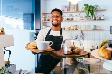 Fırın, kafede hamur işi, kahve ve fırında yemek servisi için hazır İspanyol siyahi bir adamın mutlu portresi. Restoran, kafe ve kendine güvenen garson barista servis, yardım ve hoş geldiniz.