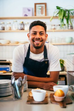 Fırın, kafede hamur işi, kahve ve fırında yemek servisi için hazır İspanyol siyahi bir adamın mutlu portresi. Restoran, kafe ve kendine güvenen garson barista servis, yardım ve hoş geldiniz.