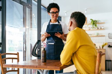 Bakery, happy portrait of black woman in cafe ready for serving pastry, coffee and baked foods. Restaurant, coffee shop and confident waiter barista by counter for service, help and welcome