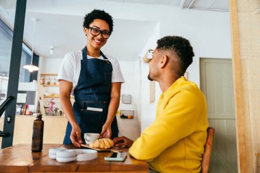 Fırın, kafedeki siyah kadının mutlu portresi pasta, kahve ve pişmiş yiyecekler servis etmeye hazır. Restoran, kafe ve kendine güvenen garson barista servis, yardım ve hoş geldiniz.