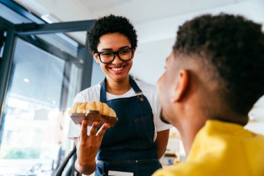 Fırın, kafedeki siyah kadının mutlu portresi pasta, kahve ve pişmiş yiyecekler servis etmeye hazır. Restoran, kafe ve kendine güvenen garson barista servis, yardım ve hoş geldiniz.