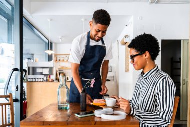 Fırın, kafede hamur işi, kahve ve fırında yemek servisi için hazır İspanyol siyahi bir adamın mutlu portresi. Restoran, kafe ve kendine güvenen garson barista servis, yardım ve hoş geldiniz.