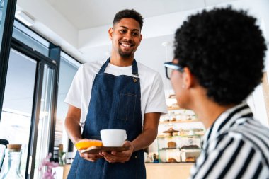 Fırın, kafede hamur işi, kahve ve fırında yemek servisi için hazır İspanyol siyahi bir adamın mutlu portresi. Restoran, kafe ve kendine güvenen garson barista servis, yardım ve hoş geldiniz.