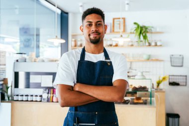 Fırın, kafede hamur işi, kahve ve fırında yemek servisi için hazır İspanyol siyahi bir adamın mutlu portresi. Restoran, kafe ve kendine güvenen garson barista servis, yardım ve hoş geldiniz.
