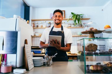 Fırın, kafede hamur işi, kahve ve fırında yemek servisi için hazır İspanyol siyahi bir adamın mutlu portresi. Restoran, kafe ve kendine güvenen garson barista servis, yardım ve hoş geldiniz.