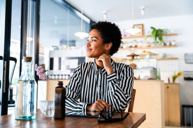 Kısa saçlı, güzel Afrikalı bir kadın, bir bar kafeteryasında oturuyor oldukça neşeli, Afro-Amerikalı bir kadın, bir pastanede dinleniyor.