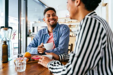 Güzel, genç, melez bir çift, bir bar kafeteryasında oturuyor, Afro-Amerikan arkadaşları bir pastanede dinleniyorlar.