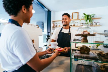 Pastane, kafede hamur işi, kahve ve fırında yemek servisi yapmaya hazır zenci erkek ve kadının mutlu portresi. Servis için tezgah, yardım ve bir kahve dükkanına hoş geldiniz.