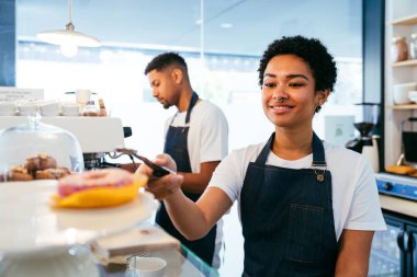 Pastane, kafede hamur işi, kahve ve fırında yemek servisi yapmaya hazır zenci erkek ve kadının mutlu portresi. Servis için tezgah, yardım ve bir kahve dükkanına hoş geldiniz.
