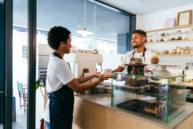 Pastane, kafede hamur işi, kahve ve fırında yemek servisi yapmaya hazır zenci erkek ve kadının mutlu portresi. Servis için tezgah, yardım ve bir kahve dükkanına hoş geldiniz.